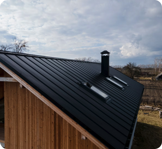 Modern black metal roofing on a wooden house under a cloudy sky