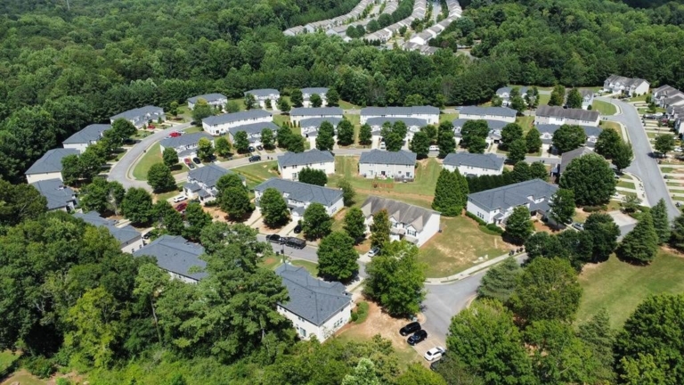 Aerial view of a suburban neighborhood with multiple homes featuring newly installed residential roofs surrounded by trees