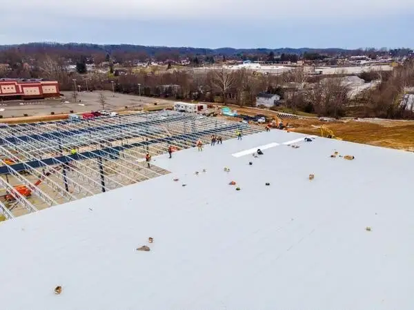 Aerial view of a large industrial roof installation in progress with construction workers on site in Atlanta